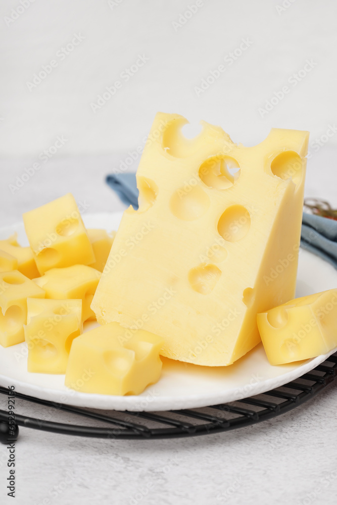 Stand and plate with pieces of Swiss cheese on white table