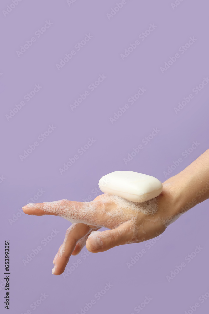 Hand with soap on lilac background