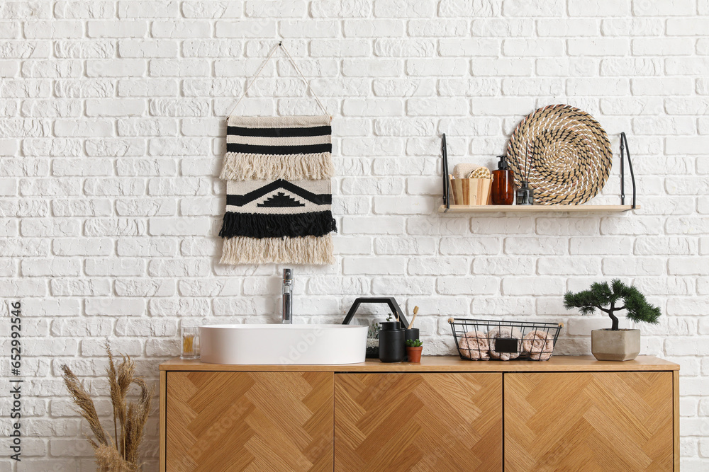 Sink bowl, bath accessories and bonsai tree on wooden cabinet in bathroom