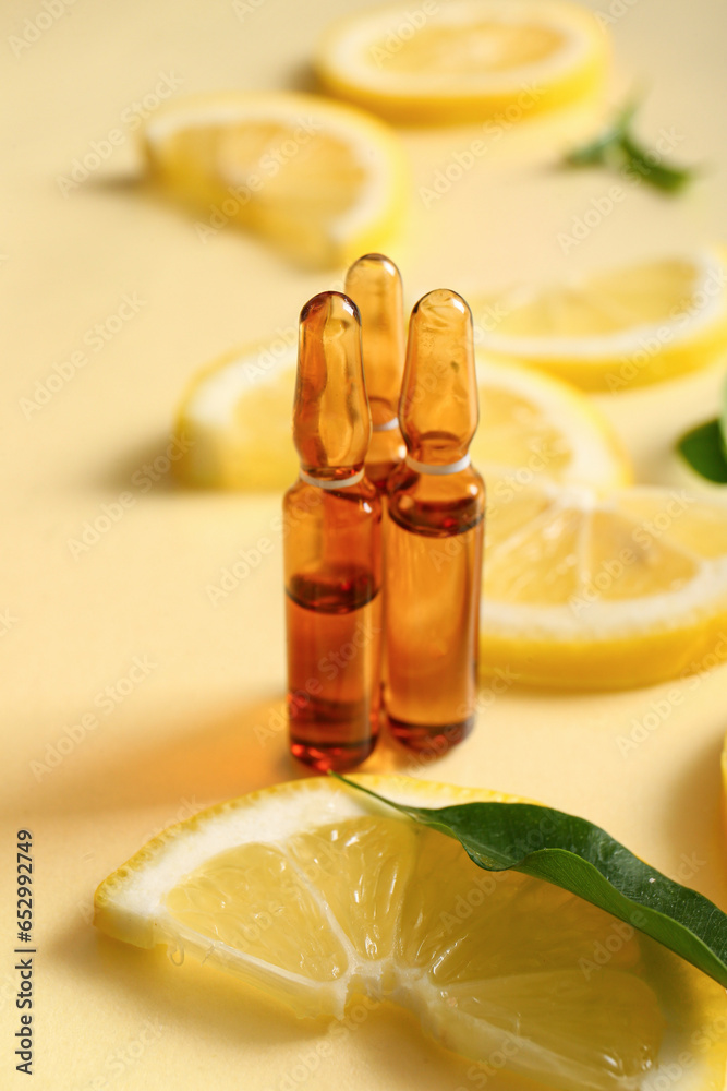 Ampoules with vitamin C and lemon slices on yellow background