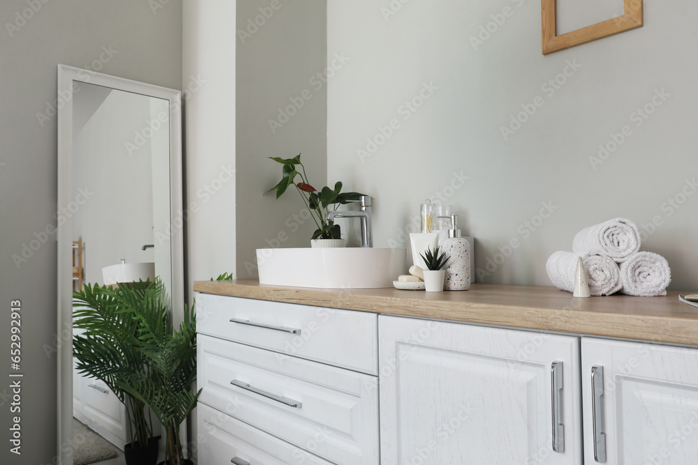 Sink bowl and bath accessories on white counters in bathroom