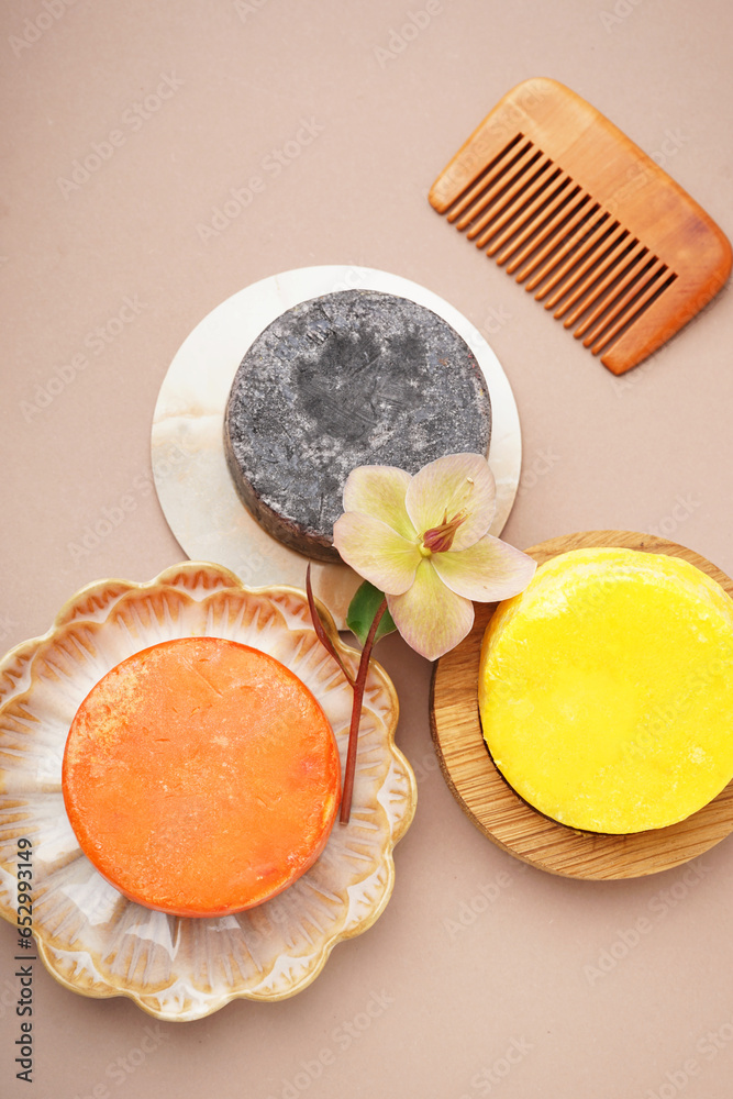 Solid shampoo bars with comb and flower on beige background