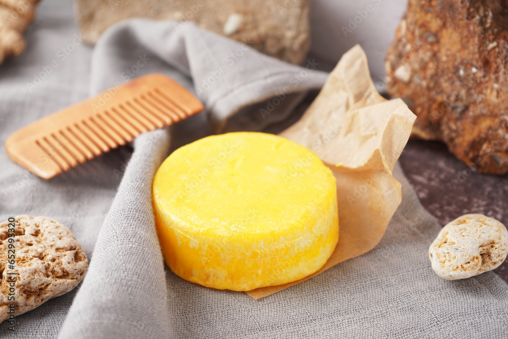 Yellow handmade solid shampoo, hair comb and stones on table, closeup