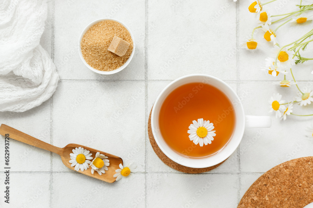 Cup of hot chamomile tea on white tile background