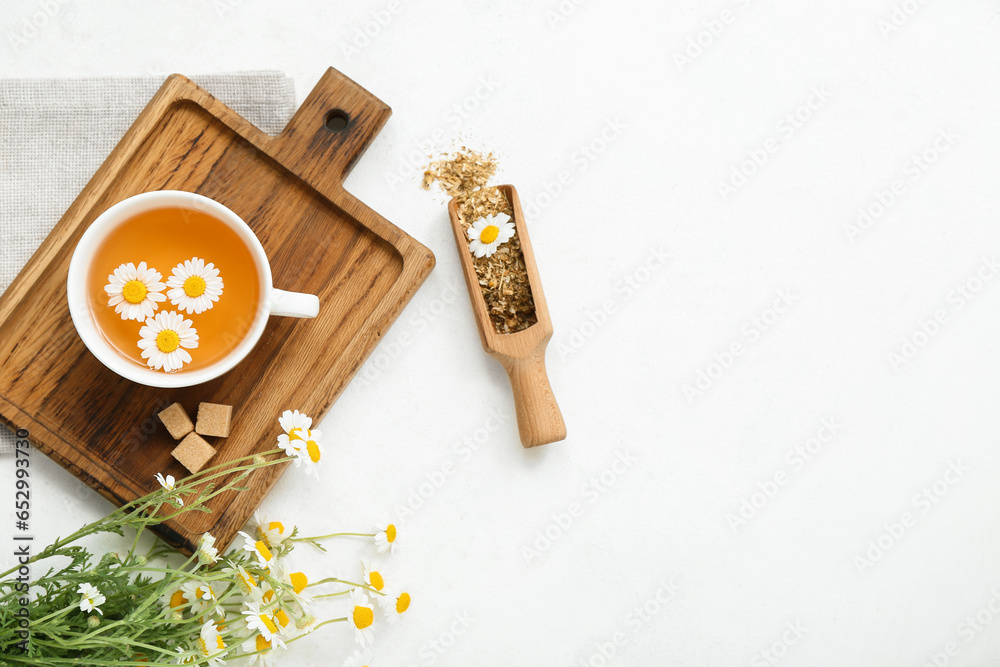 Cup of hot chamomile tea on light background