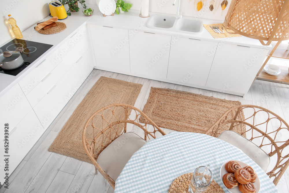 Stylish wicker rugs in interior of modern kitchen