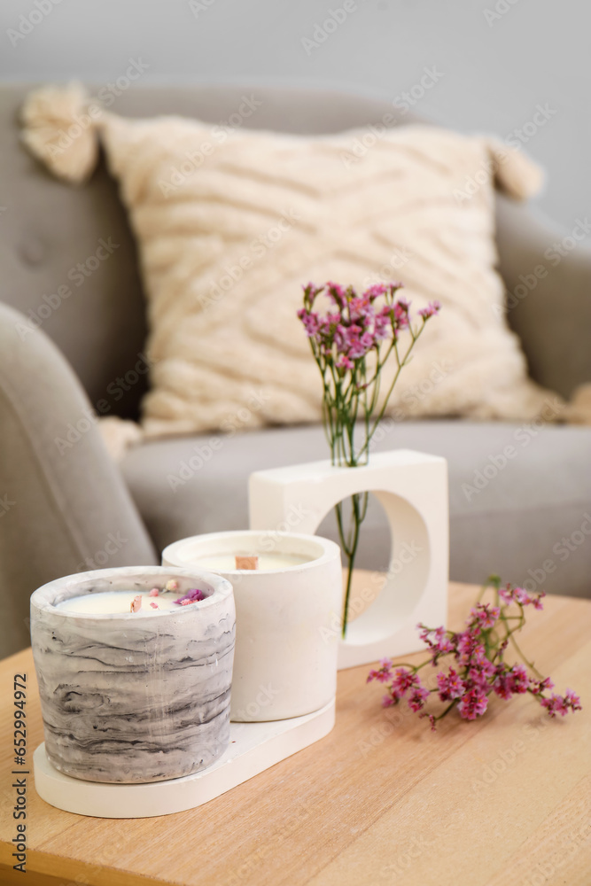 Interior of light living room with candles and flowers on table, closeup