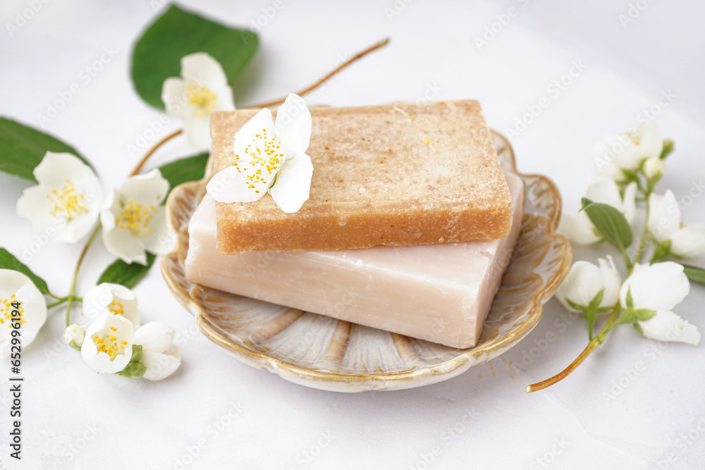 Plate with soap bars and beautiful jasmine flowers on light background, closeup