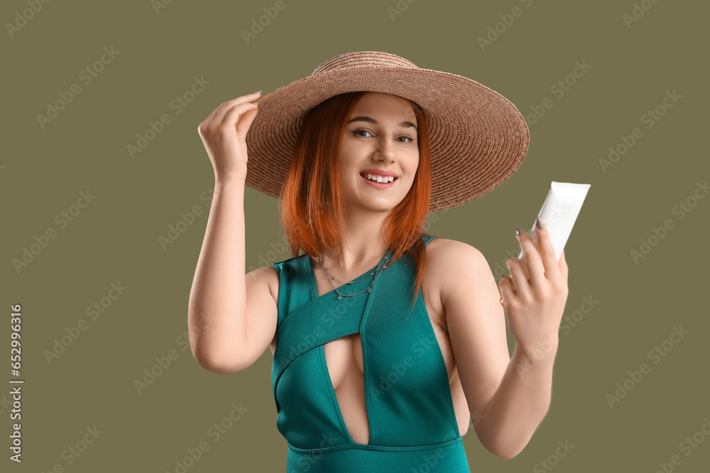 Young woman with sunscreen cream on green background