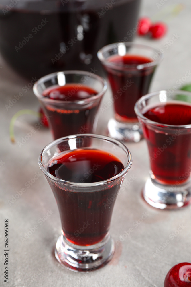 Shots with sweet cherry liqueur on grey background