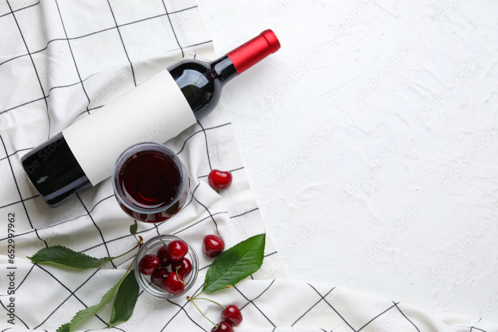 Glass and bottle with sweet cherry liqueur on white background