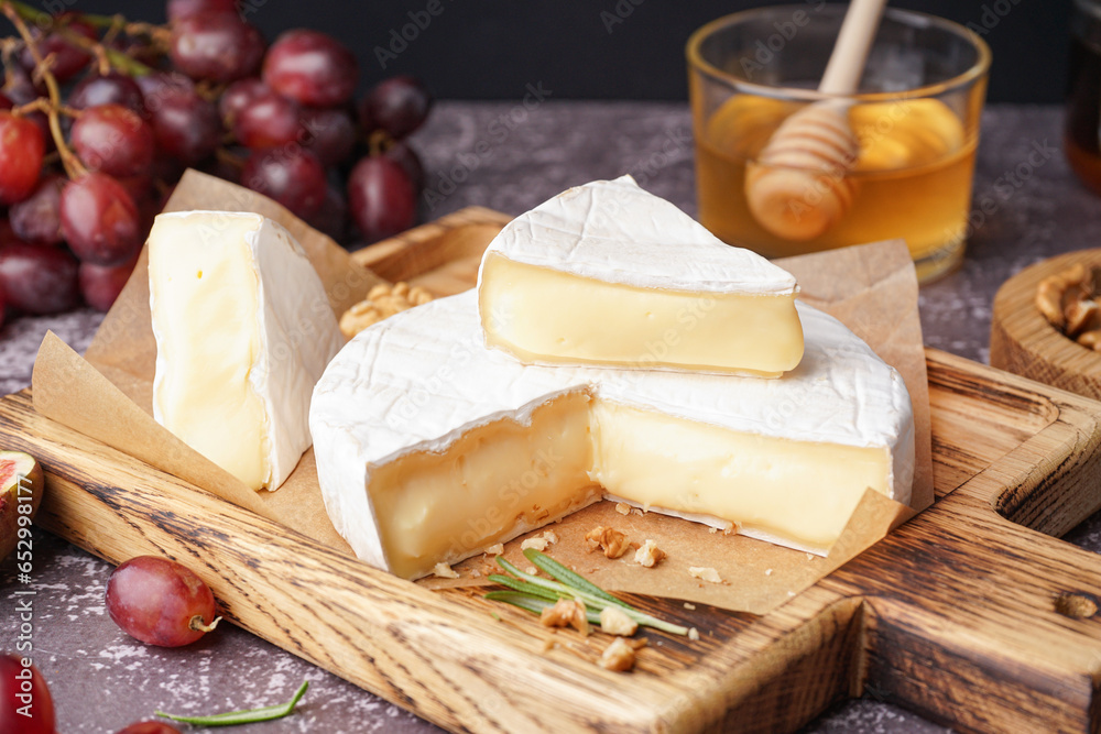 Wooden board with tasty Camembert cheese on table