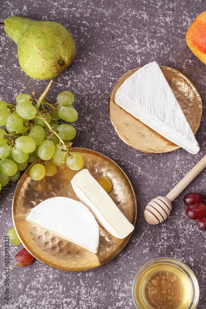 Plates with pieces of tasty Camembert cheese on grey background