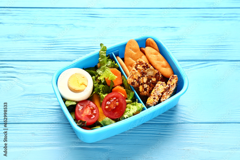 Lunchbox with tasty food on blue wooden background