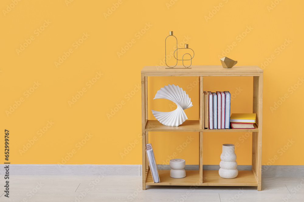 Shelving unit with books and decor near orange wall in room