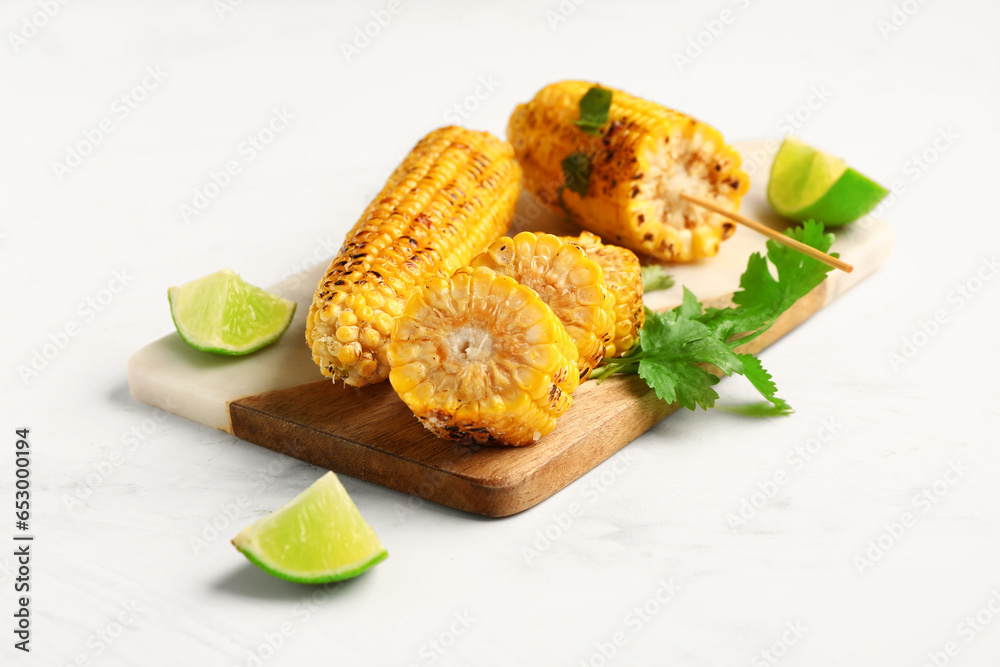 Board with tasty grilled corn cobs and parsley on white background