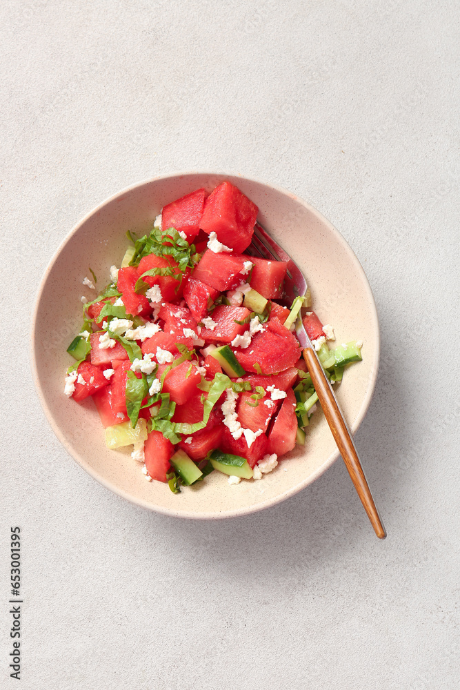 Bowl of tasty watermelon salad on light background