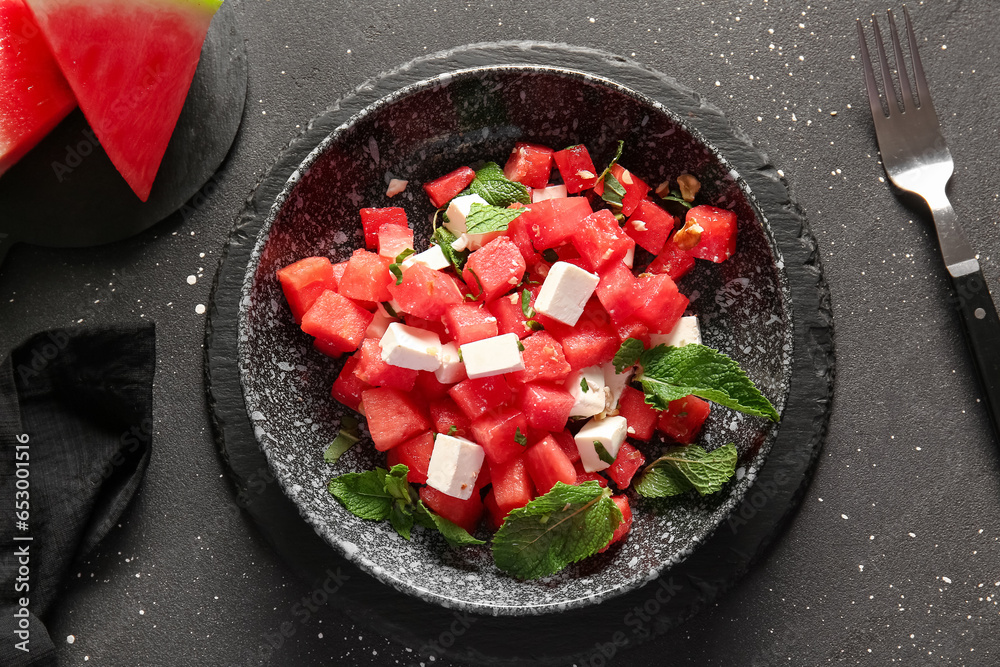 Bowl of tasty watermelon salad on black background