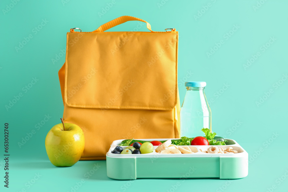 Bag, bottle of water and lunchbox with tasty food on turquoise background