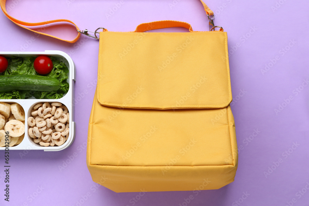 Bag and lunchbox with tasty food on lilac background