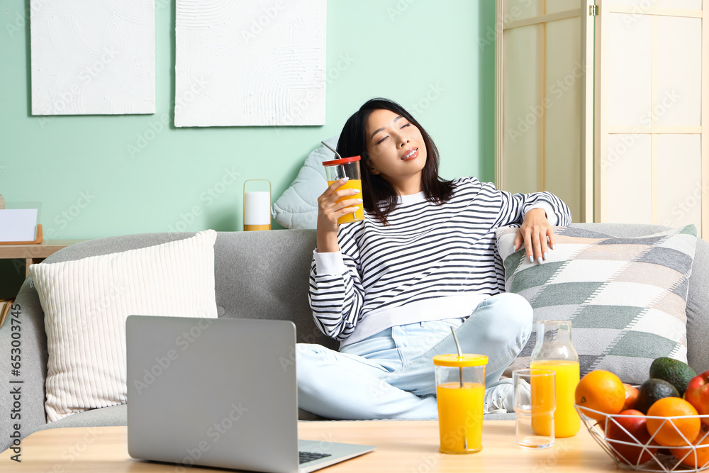 Beautiful Asian woman with glass of juice at home