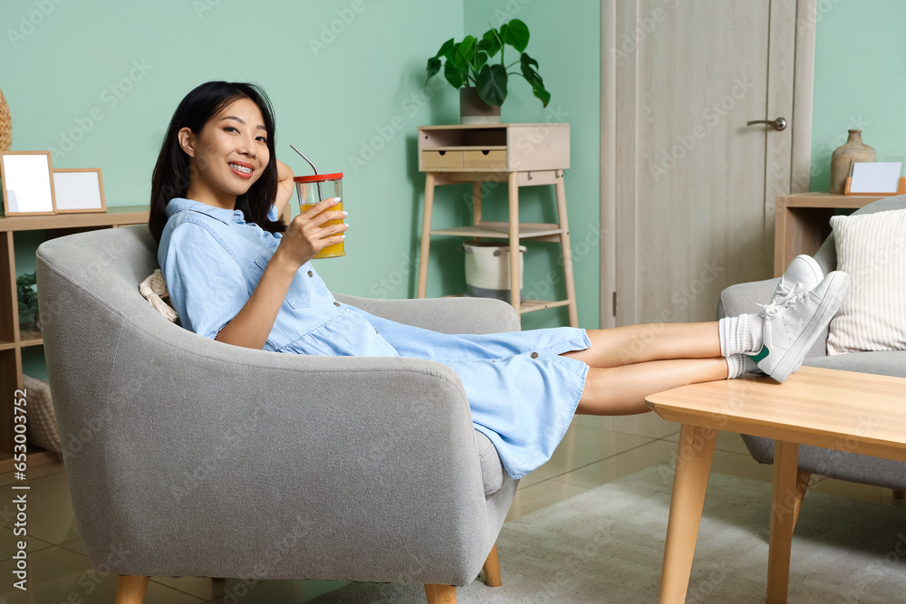 Beautiful Asian woman with glass of juice at home