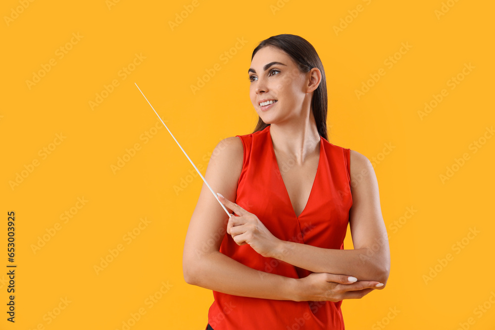 Young female teacher with pointer on yellow background