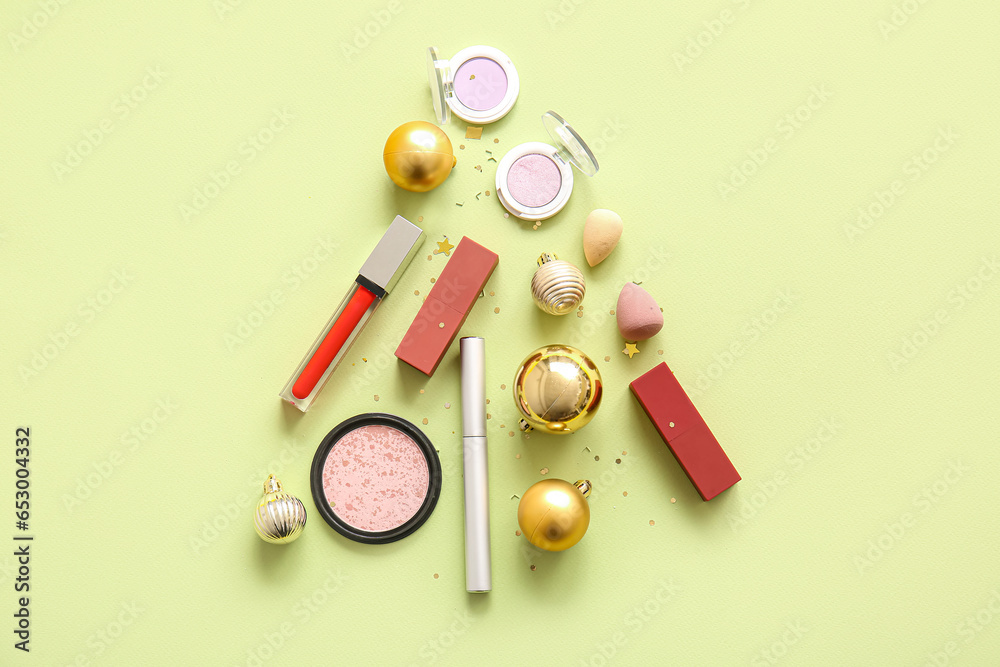 Christmas tree made of makeup cosmetics and golden balls on light yellow background