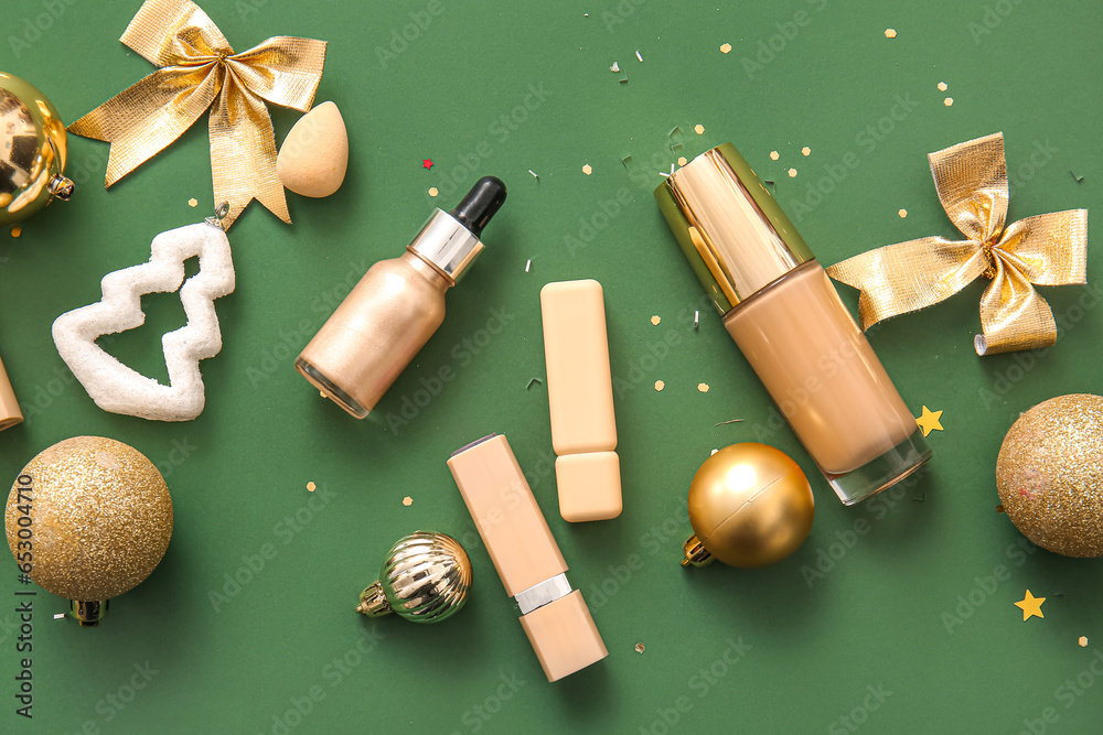 Composition with makeup products and golden Christmas decor on dark green background