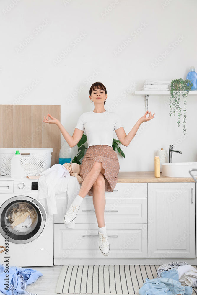 Young woman meditating in laundry room