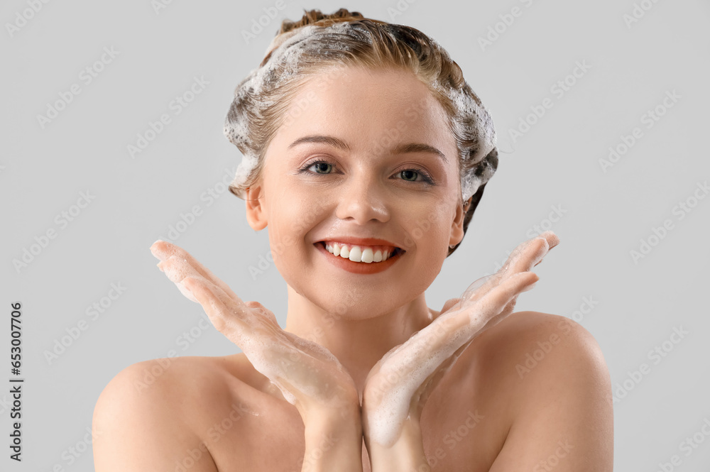 Young woman with shampoo on light background, closeup