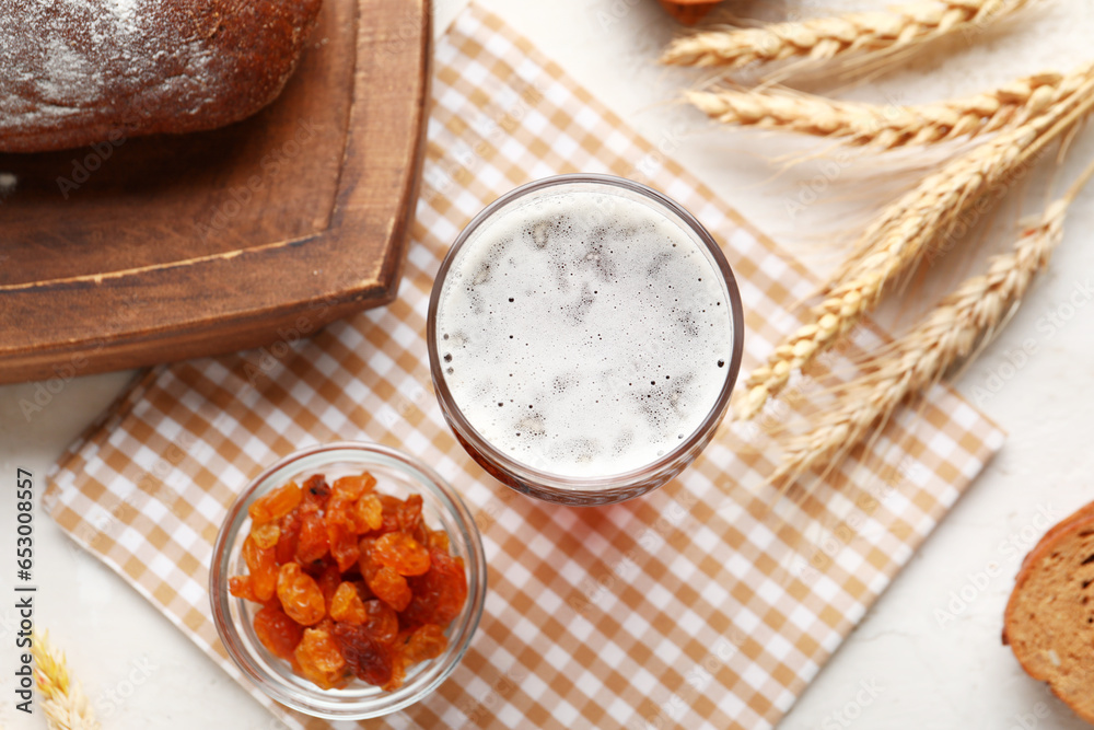 Glass of tasty kvass and raisins on white background