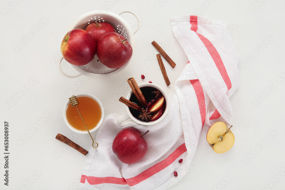 Cup of hot mulled wine with apple and bowl of honey on white background