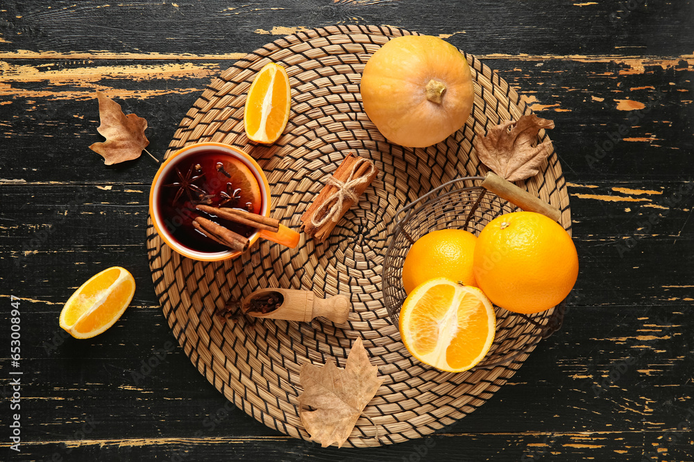 Cup of hot mulled wine with orange and cinnamon on black wooden background