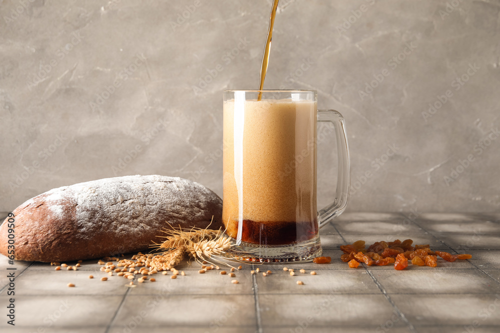 Pouring of tasty kvass into mug on table