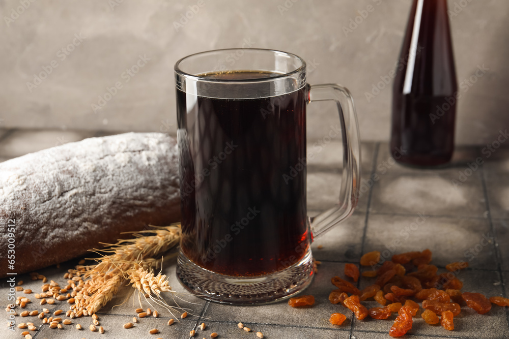 Mug of tasty kvass, bread, raisins and wheat grains on table