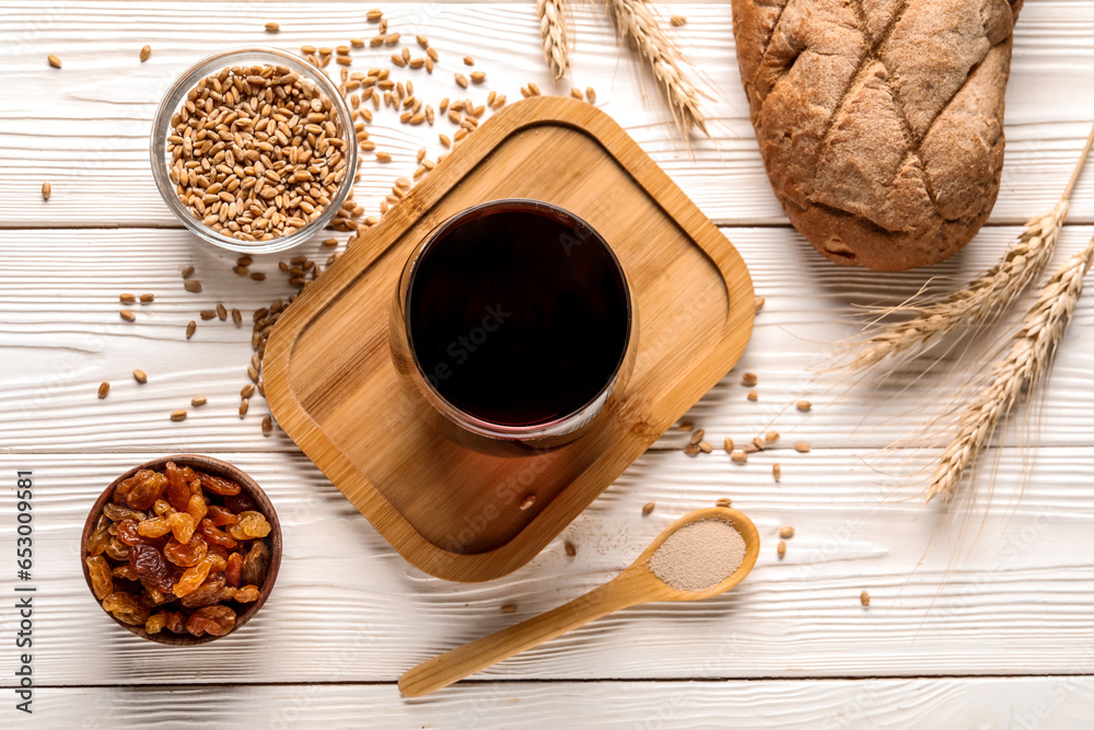 Glass of tasty kvass and ingredients on white wooden background