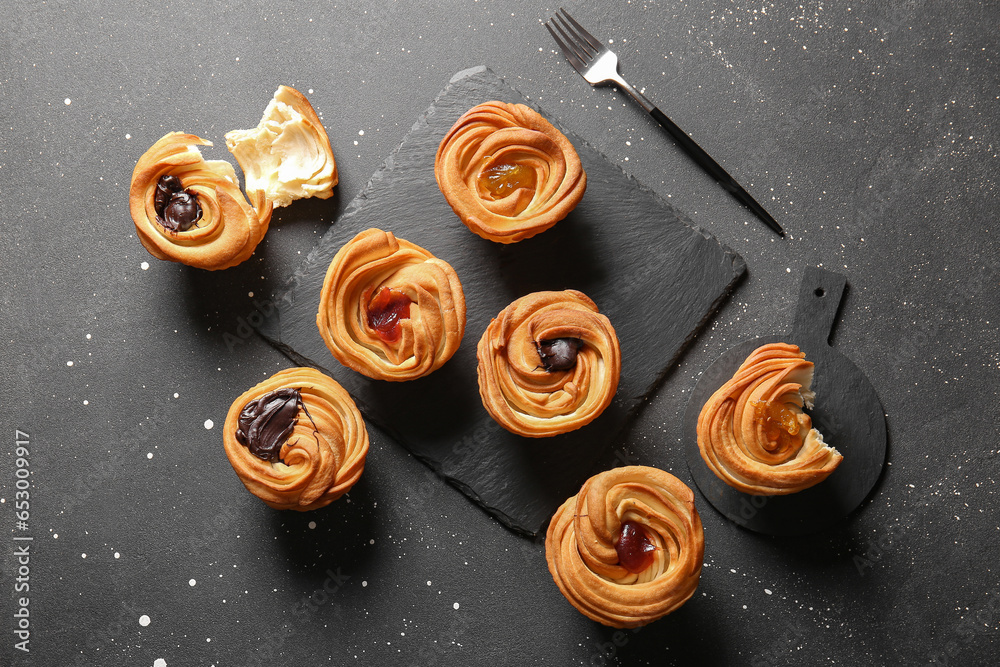 Boards of tasty cruffins with chocolate and jam on black background