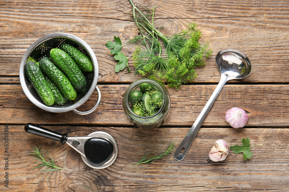 Fresh cucumbers and ingredients for canning on wooden background