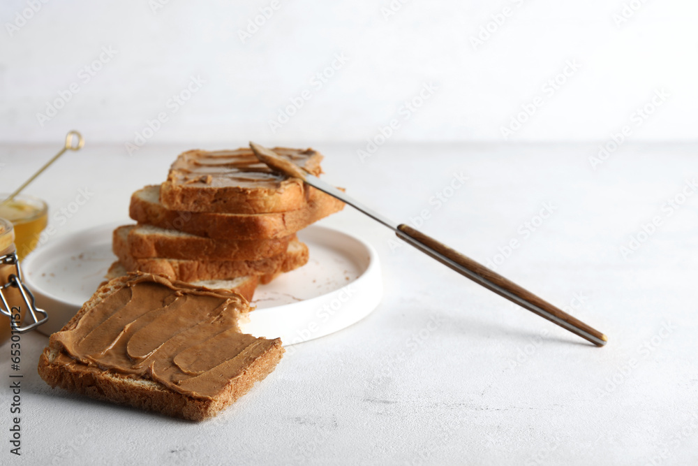 Plate of toasts with peanut butter on white background