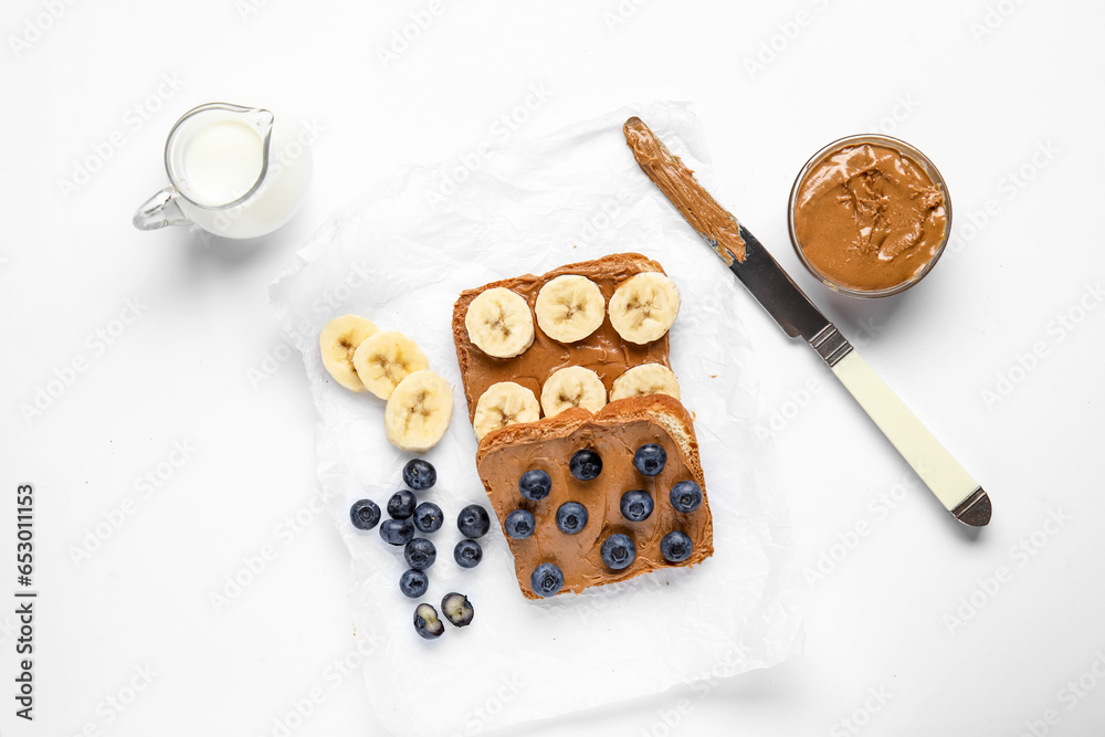 Baking paper of toasts with peanut butter and fresh fruits on white background