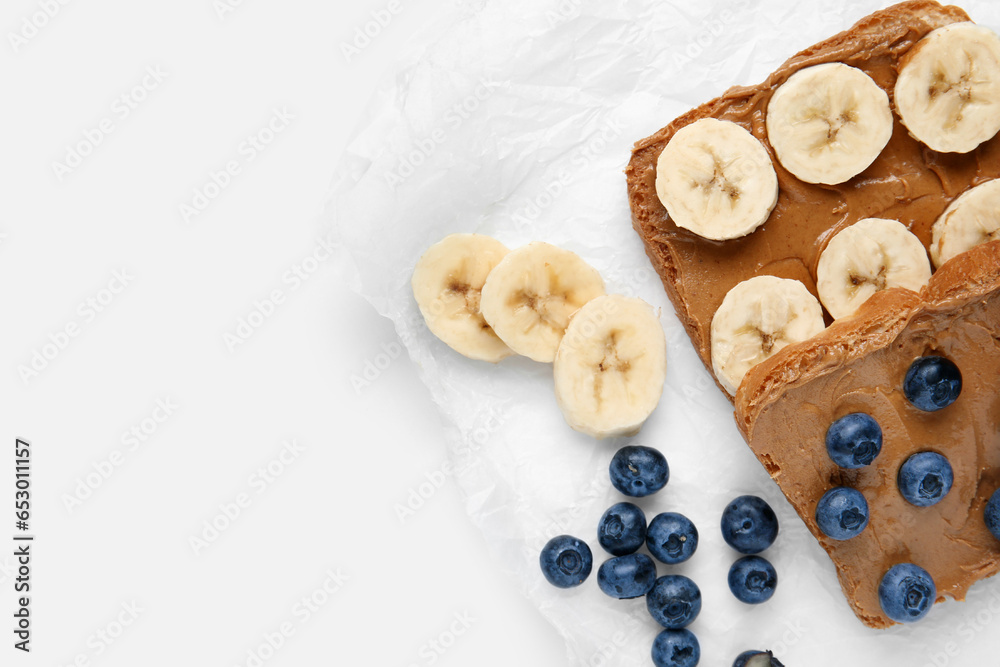 Baking paper of toasts with peanut butter and fresh fruits on white background