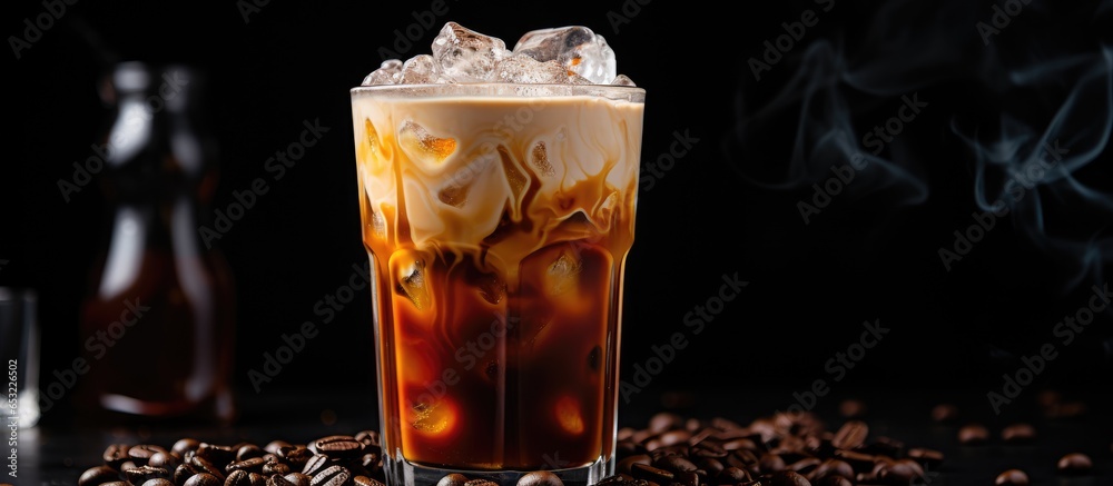 Iced coffee in a glass with coffee ice cubes and milk cream on the table