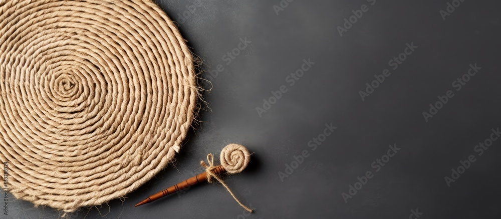 Jute napkin and crochet hook on gray background representing needlework hobby