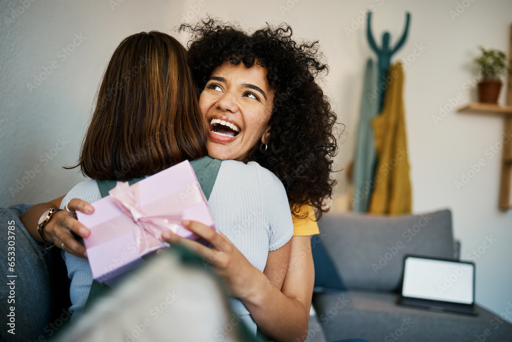 Excited, hug and present for birthday of girl friends and smile on living room sofa. Surprise, gift and happy female person at home with giving in lounge with celebration, congratulations and package