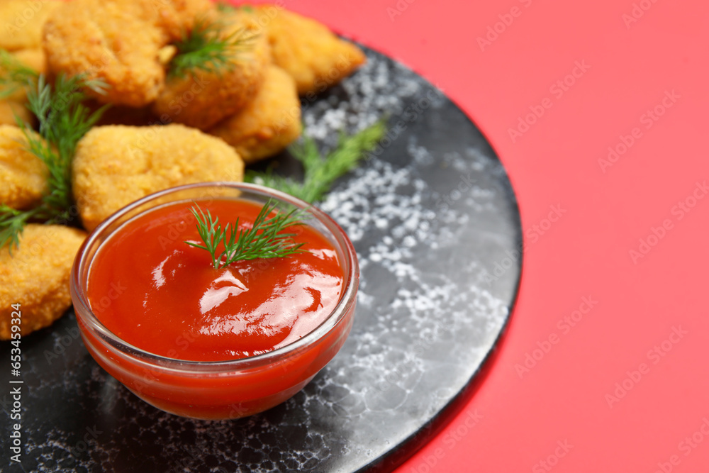 Slate board of tasty nuggets with ketchup on red background, closeup