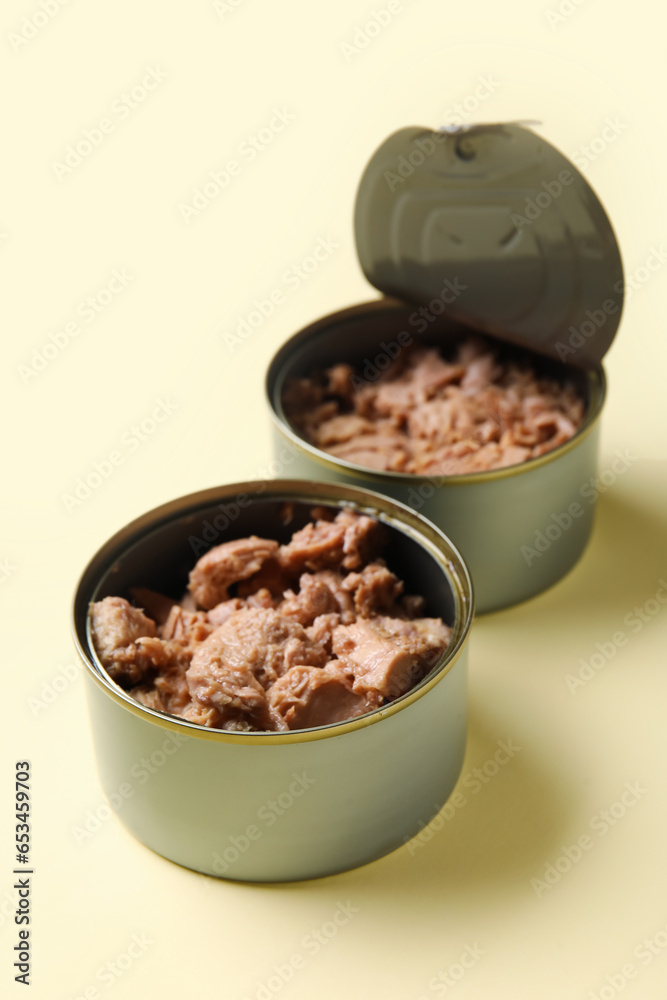 Opened tin cans with delicious tuna on beige background