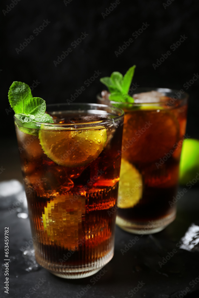 Glasses of tasty Cuba Libre cocktail on dark background