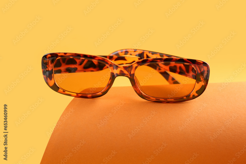 Stylish sunglasses on color background