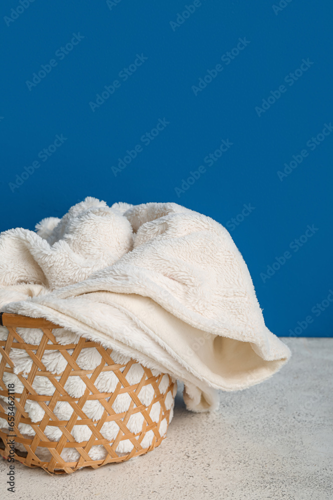 Basket with new soft blanket near blue wall